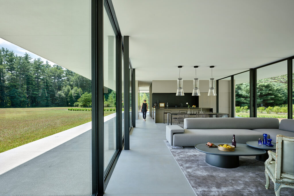 A streamlined modern kitchen island with waterfall edge sits between two large open doorways.